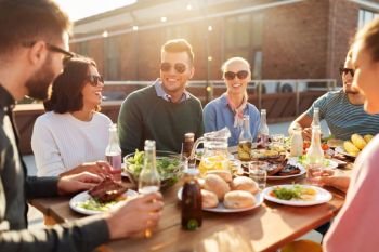 leisure and people concept - happy friends having dinner or bbq party on rooftop in summer. friends having dinner or bbq party on rooftop