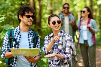 travel, tourism, hike and people concept - group of friends with map and backpacks in forest. friends with map and backpacks hiking in forest