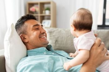 family, parenthood and fatherhood concept - happy smiling middle aged father with little baby daughter lying on sofa at home. middle aged father with baby lying on sofa at home