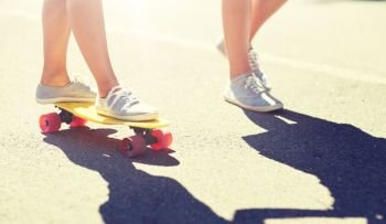 summer, extreme sport and people concept - feet of teenage couple riding short modern cruiser skateboard on road. feet of teenage couple riding skateboard on road
