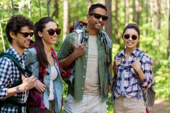 travel, tourism, hike and people concept - group of friends with backpacks in forest. group of friends with backpacks hiking in forest