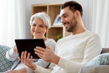 family, generation and technology concept - happy smiling senior mother and adult son with tablet computer at home. old mother and adult son with tablet pc at home