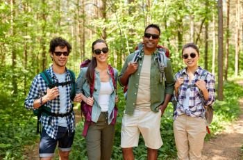 travel, tourism, hike and people concept - group of friends with backpacks in forest. friends with backpacks on hike in forest