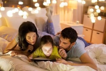 people and family concept - mother, father and little daughter with tablet pc computer in bed at night at home. family with tablet pc in bed at night at home