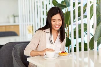 leisure, people and lifestyle concept - smiling young asian woman eating cake with coffee at cafe. asian woman eating cake with coffee at cafe