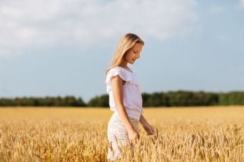nature, harvest and people concept - smiling young girl on cereal field in summer. smiling young girl on cereal field in summer