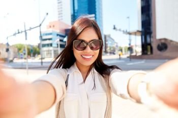 communication, lifestyle and technology concept - smiling young asian woman in sunglasses taking selfie on city street. smiling woman in sunglasses taking selfie in city