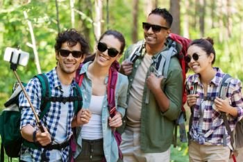 travel, tourism, hike and people concept - group of friends with backpacks taking selfie by smartphone in forest. friends with backpacks hiking and taking selfie