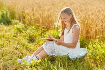 country, literature and leisure concept - smiling young girl in white dress writing to diary on cereal field in summer. smiling girl writing to diary on cereal field