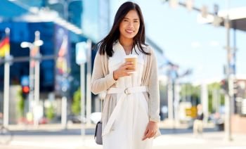 lifestyle and people concept - happy smiling young asian woman with takeaway coffee cup on city street. smiling woman with takeaway coffee cup in city