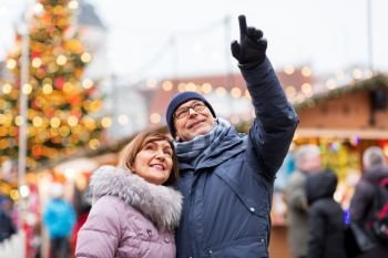 travel, tourism, holidays and people concept - happy senior couple hugging at christmas market on town hall square in tallinn, estonia. happy senior couple hugging at christmas market