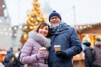 love, winter holidays and people concept - happy senior couple with takeaway coffee at christmas market on town hall square in tallinn, estonia. senior couple with coffee at christmas market