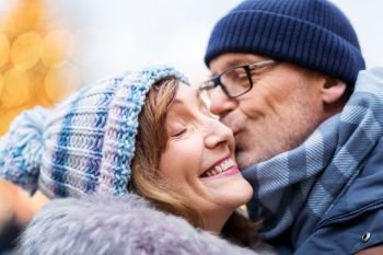 love, christmas and people concept - close up of happy senior couple kissing outdoors in winter. close up of happy senior couple kissing in winter
