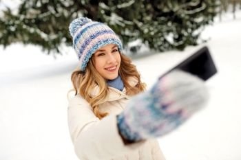 people, season and leisure concept - happy smiling woman taking selfie by smartphone in winter. woman taking selfie by smartphone in winter