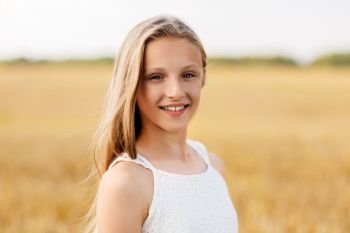 nature and people concept - smiling young girl on cereal field in summer. smiling young girl on cereal field in summer