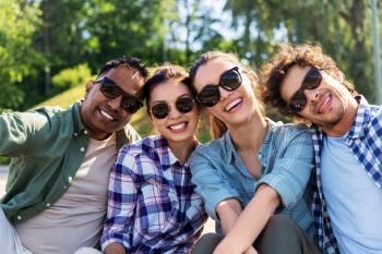 leisure and people concept - group of happy friends hanging out and taking selfie at summer park. happy friends taking selfie at summer park