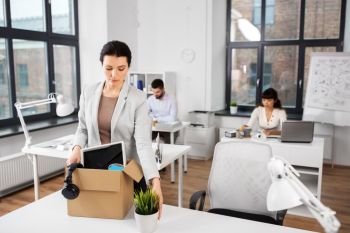 business, firing and job loss concept - sad fired female office worker with box of her personal stuff. female office worker with box of personal stuff