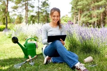 gardening, technology and people concept - happy young woman or gardener with tablet computer and garden tools in summer. woman with tablet pc and garden tools in summer
