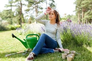 gardening and people concept - tired young woman or gardener with garden tools in summer. tired young woman with garden tools in summer