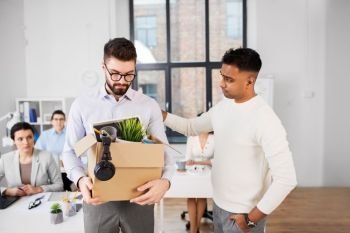 business, firing and job loss concept - colleague seeing off sad fired male office worker holding box of his personal stuff. colleague seeing off sad fired male office worker