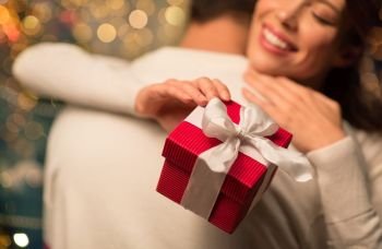 winter holidays and people concept - close up of happy couple with christmas gift hugging at home. close up of couple with christmas gift hugging