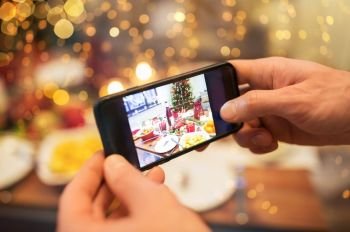 technology, eating and holidays concept - close up of male hands photographing food by smartphone at christmas dinner. hands photographing food at christmas dinner