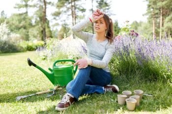 gardening and people concept - tired young woman or gardener with garden tools in summer. tired young woman with garden tools in summer