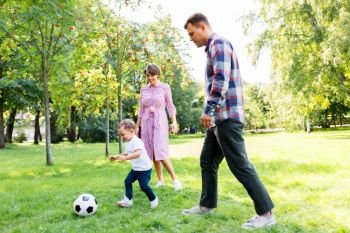 family, leisure and people concept - happy mother, father and little son with ball playing soccer at summer park. happy family playing soccer at summer park