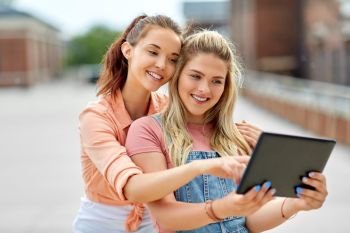 technology, leisure and people concept - happy smiling teenage girls or best friends with tablet pc computer on roof top in summer. teenage girls with tablet computer on roof top