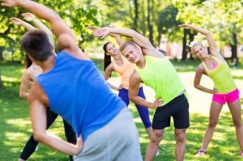 fitness, sport and healthy lifestyle concept - group of happy people exercising at summer park. group of happy people exercising at summer park