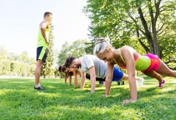 fitness, sport and healthy lifestyle concept - group of people with coach exercising at park in summer at boot camp. group of people exercising at park in summer