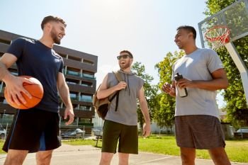 sport, leisure games and male friendship concept - group of men or friends laughing on basketball court outdoors. group of male friends going to play basketball