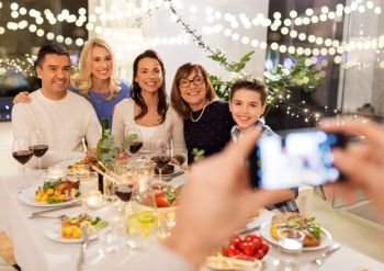 celebration, holidays and people concept - happy family having dinner party at home and photographing by smartphone. family photographing by smartphone at dinner party