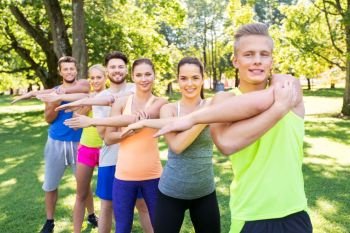 fitness, sport and healthy lifestyle concept - group of happy people exercising at summer park or boot camp. group of happy people exercising at summer park