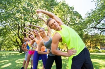 fitness, sport and healthy lifestyle concept - group of happy people exercising at summer park or boot camp. group of happy people exercising at summer park