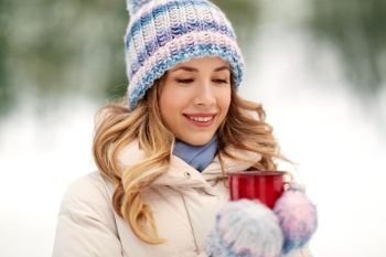people, season, drinks and leisure concept - close up of happy young woman with tea cup outdoors in winter. happy young woman with tea cup outdoors in winter