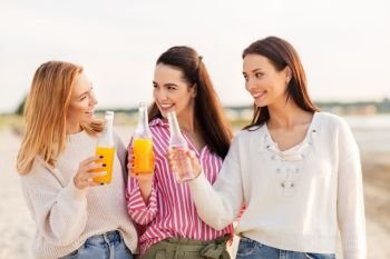 friendship and leisure concept - group of happy young women or female friends toasting non alcoholic drinks on summer beach. young women toasting non alcoholic drinks on beach