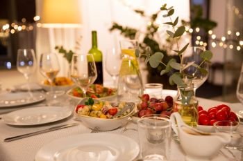 celebration, holidays, catering and eating concept - table served with plates, wine glasses and food for home dinner party. table served with plates, wine glasses and food