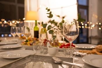 celebration, holidays, catering and eating concept - table served with plates, wine glasses and food for home dinner party. table served with plates, wine glasses and food