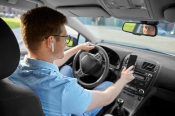 transport, vehicle and people concept - man or driver with wireless earphones driving car and using gps navigator on smartphone. man driving car and using gps on smartphone