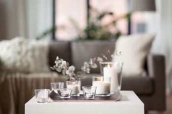 decoration, hygge and cosiness concept - burning white fragrance candles on tray and branches of eucalyptus populus on table at cozy home. burning fragrance candles on table at cozy home