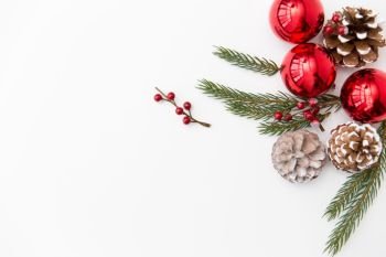 winter holidays, new year and decorations concept - red christmas balls and fir branches with pine cones on white background. christmas balls and fir branches with pine cones