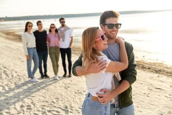 friendship, leisure and people concept - happy couple and group of friends on beach in summer. happy couple and group of friends on summer beach