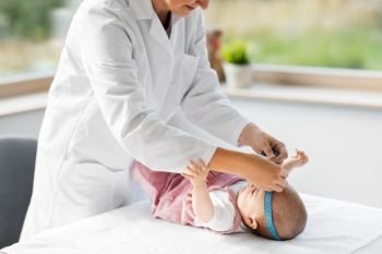 medicine, healthcare and pediatrics concept - female pediatrician doctor with measure tape measuring baby girl patient’s head at clinic or hospital. pediatrician doctor measuring bab’s head at clinic