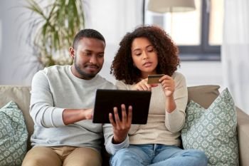 family, technology, online shopping and people concept - african american couple couple with tablet pc computer and credit card at home. couple with tablet pc and credit card at home