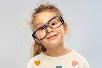 school, education and vision concept - portrait of smiling little girl in crookedly placed glasses over grey background. smiling little girl in crookedly placed glasses