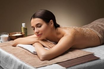 wellness, beauty and relaxation concept - beautiful young woman lying with sea salt on skin at spa. woman lying with sea salt on skin at spa