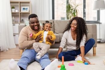 family, parenthood and people concept - happy african american mother, father and baby daughter playing with toy blocks at home. african family playing with baby daughter at home