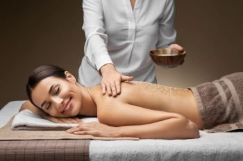 wellness, beauty and relaxation concept - beautiful young woman having salt massage at spa. beautiful young woman having salt massage at spa