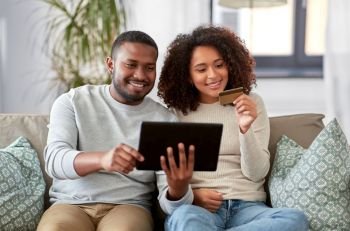 family, technology, online shopping and people concept - happy african american couple couple with tablet pc computer and credit card at home. couple with tablet pc and credit card at home